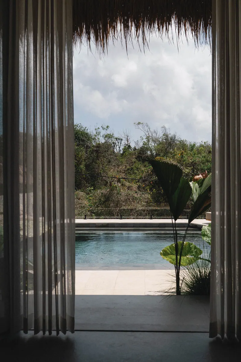 View of the pool framed by linen curtains