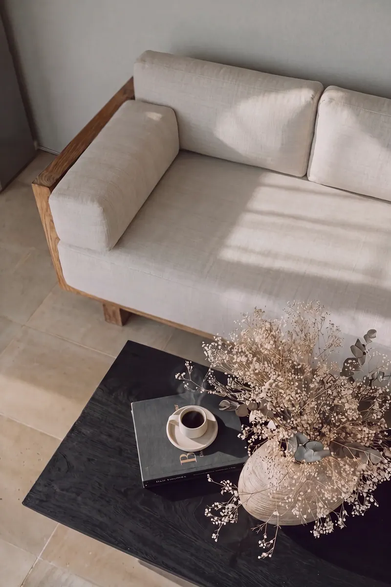 Linen sofa with a cup of coffee and dried flowers on a dark table