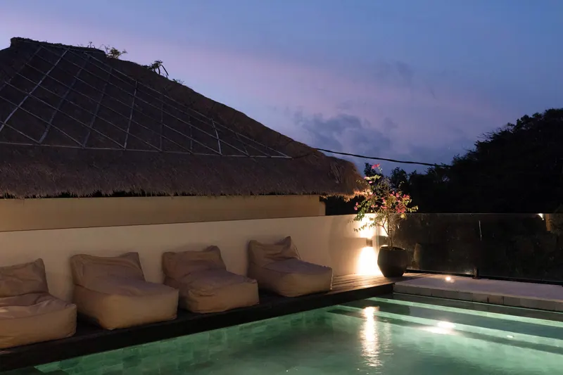 Thatched roof and pool loungers at dusk