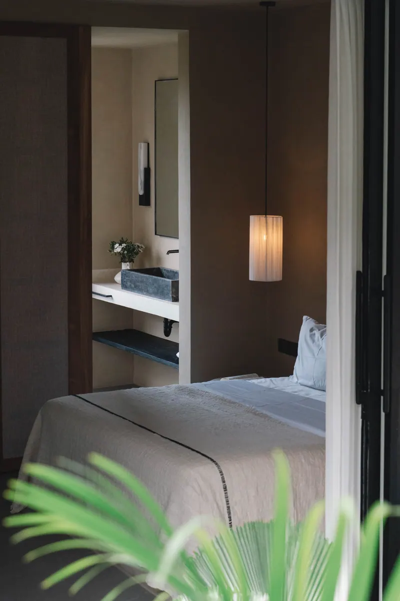 Bed and bathroom seen through the open glass door