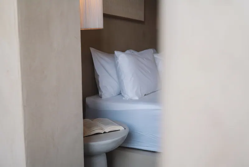 Corner of the bed beside a stone side table