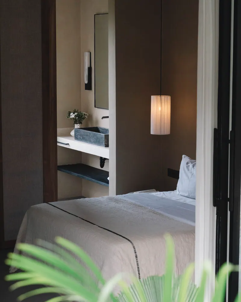 Double bed with linen bedding, a bathroom visible through the open door